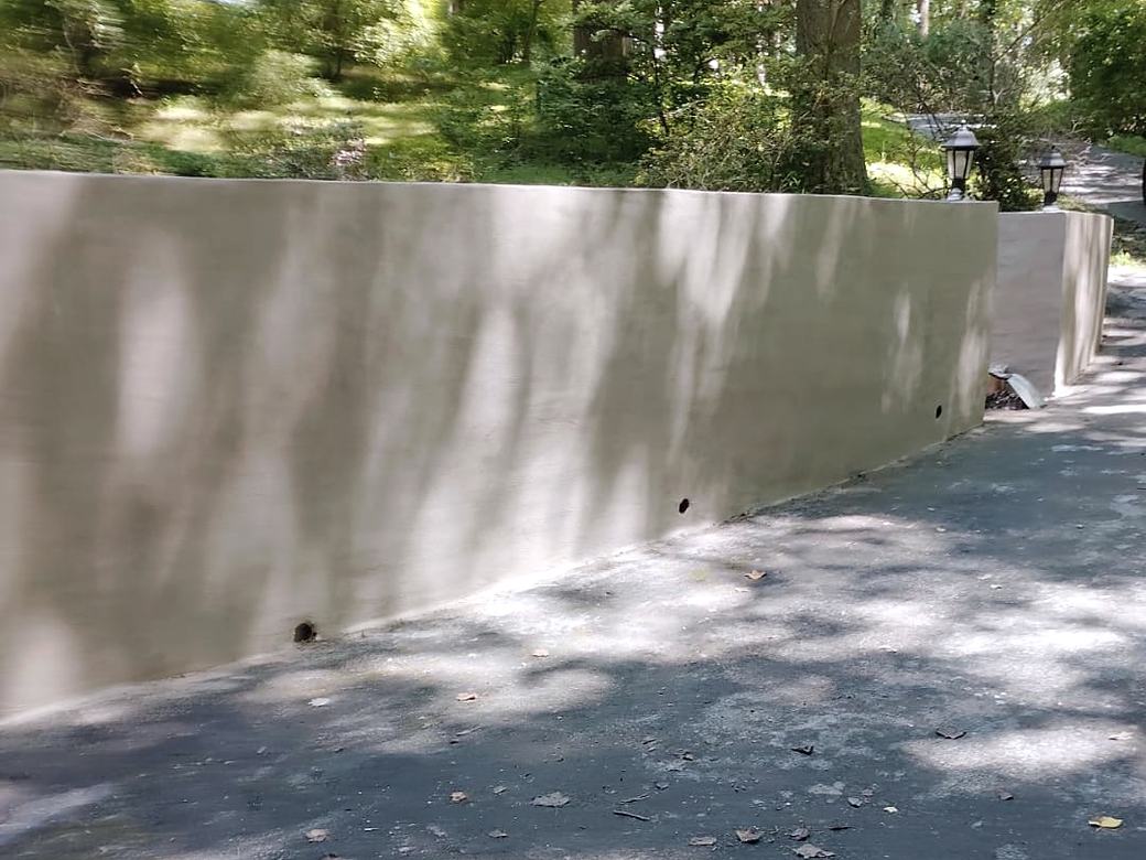 Long resurfaced concrete retaining wall along a driveway