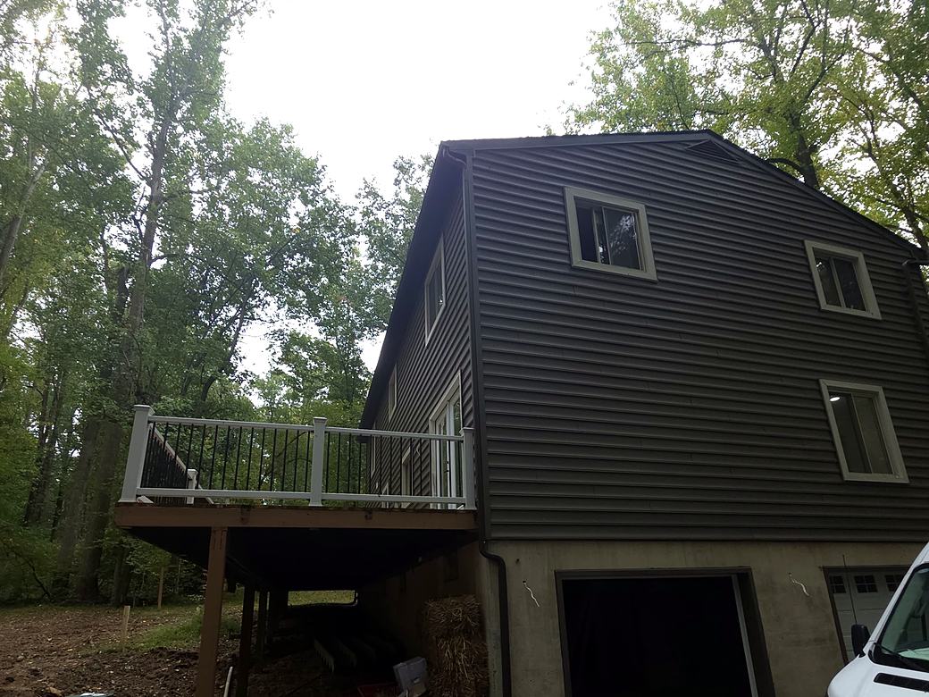 Raised deck with white railings on the side of a two story home
