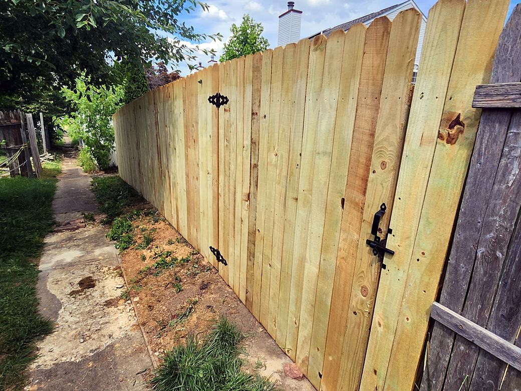 Long run of new wood privacy fence with a gate