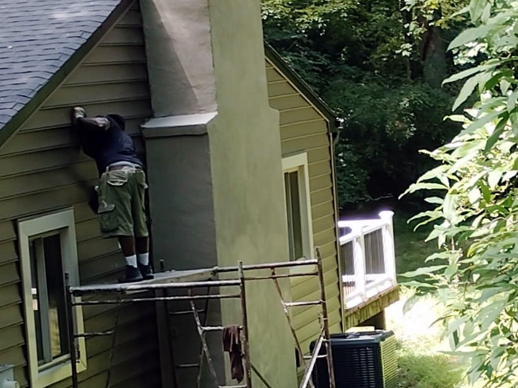 Crew member working on siding beside a chimney
