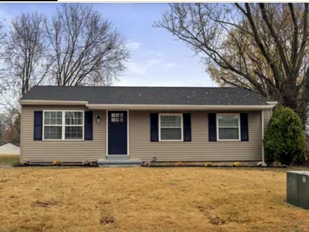 Same ranch with beige vinyl siding, navy shutters and a navy front door