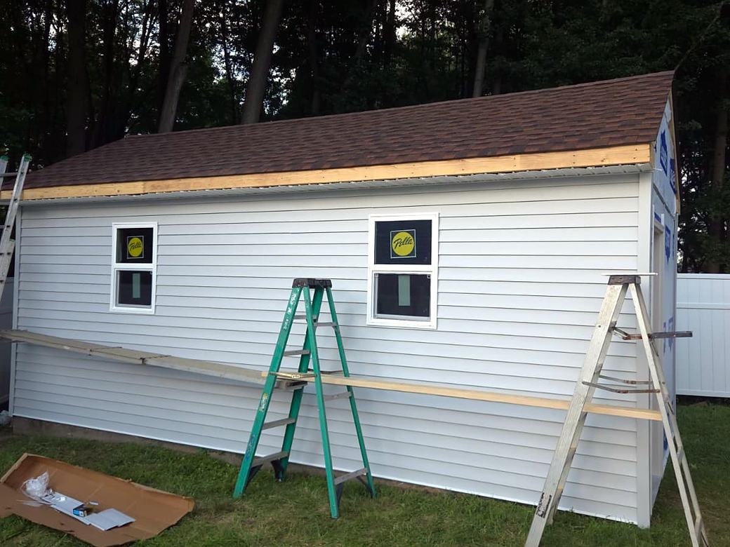 Custom shed with new white vinyl siding and shingle roof going on