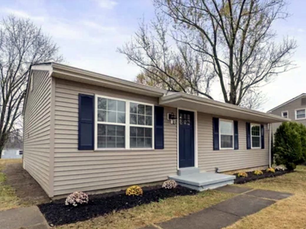 Side of a ranch home with windows trimmed in new siding