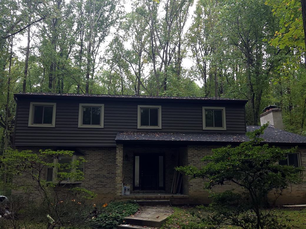 Two story home with new dark gray vinyl siding and light trim
