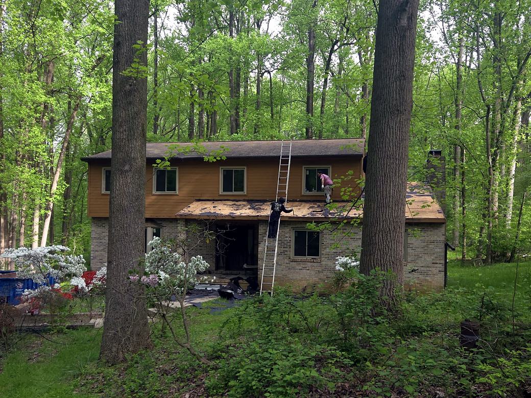 Two story home with old brown wood siding and worn roof before the work